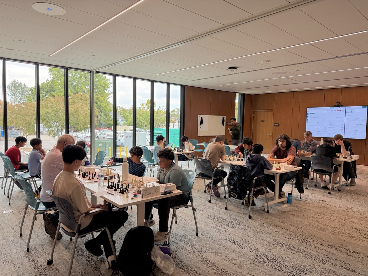 Players competing over chessboards at tables in a bright room during the C4 x SMC tournament.
