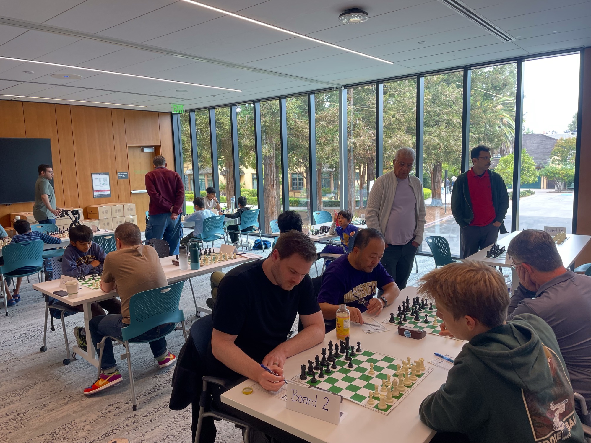 Players and families gathered around chessboards during the C4 x SMC tournament.