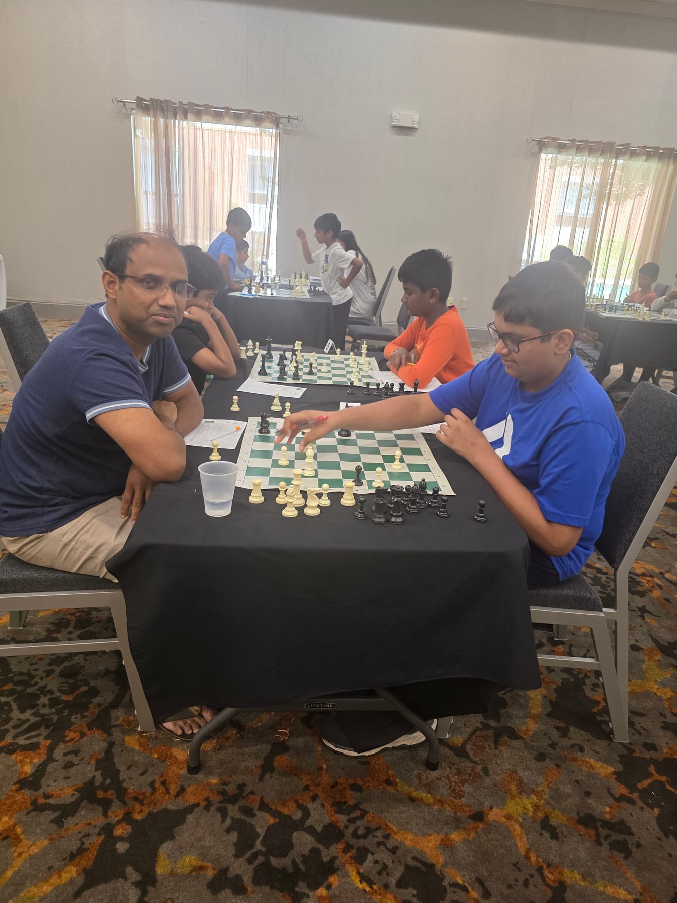 A young player reaching for a chess piece during a game.