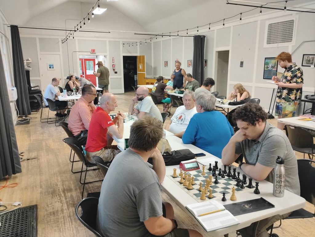 Spokane Chess Club members playing chess around tables in a club room.